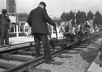 836554 Afbeelding van een wegwerker van de N.S. tijdens een demonstratie van een kraagschroefmachine op de stand van de ...